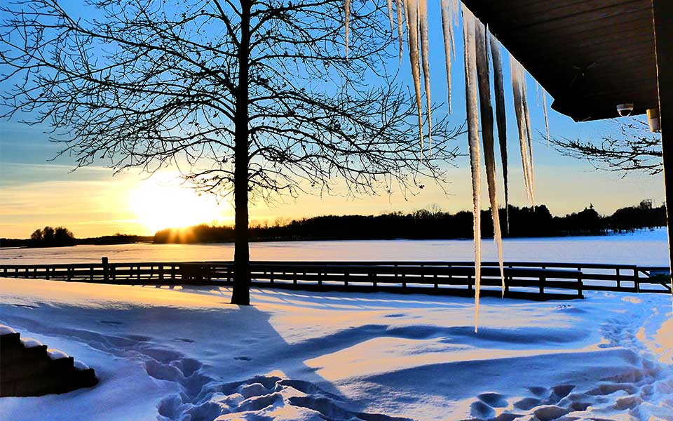 icicles hanging over snow with frozen lake in background